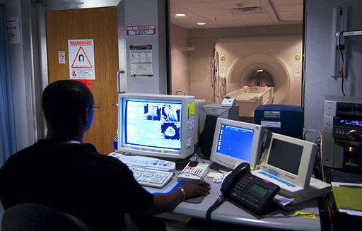Image: Technician watches a patient go through a MRI machine
